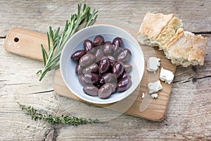 Kalamata black olives, bread, feta cheese and herbs on rustic wo