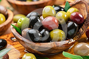 Kalamata, green and black olives in the wooden bowl. Food background