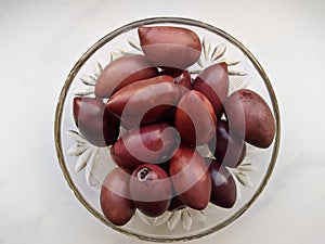 Kalamata olives in a glass bowl on a white background top view