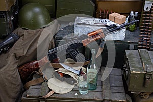 Kalashnikov AK 47 with ammunitions and vodka on army box background