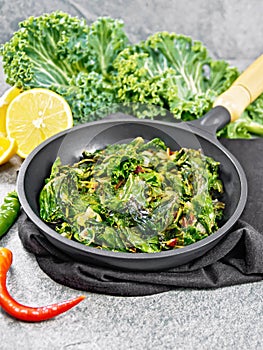 Kale cabbage with orange and pepper in pan on granite