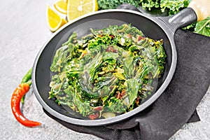 Kale cabbage with orange and pepper in pan on granite table
