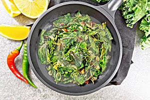 Kale cabbage with orange and pepper in pan on stone top