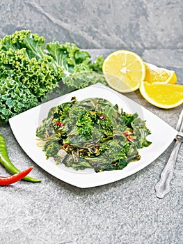 Kale cabbage with orange and pepper in plate on stone
