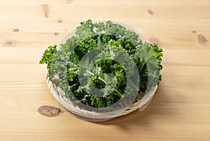 Kale in a colander placed against a wooden background