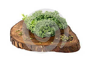 Kale leafs and pumpkin seeds on wooden cutting board