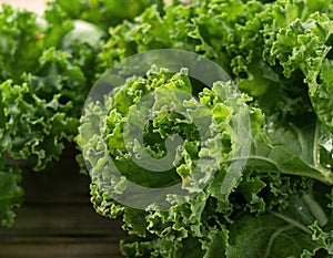 Kale placed against a wooden background. curly kale