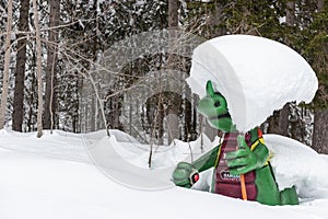 Kali the Ramsaurier, likeable, snow covered, green dinosaur mascot of ski school at ski region Ramsau Dachstein, Steiermark.