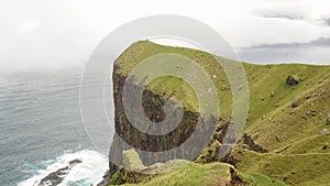 Kallur Lighthouse on Kalsoy Island in a green grass landscape on the Faroe Islands, Denmark.