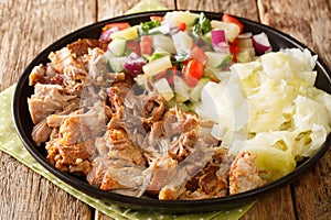 Kalua pork hawaiian food slowly cooked and served with stewed cabbage and fresh salad close-up in a plate. horizontal