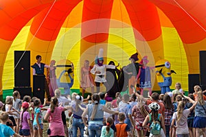 Animators on stage entertain children at the festival day of the village of Kamennomostsky in the autumn park