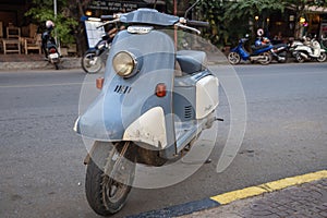 Kampot, Cambodia - 12 April 2018: blue vintage scooter on town street. Vintage bike on street. Old Julio fashion scooter