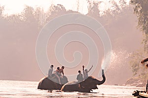 KANCHANABURI, THAILAND - FEB, 2018 : tourism ride the elephant to take a shower at Kwai river, travel and adventure activity in Th