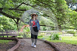 Kanchanaburi, Thailand-February 8, 2021: Unidentified woman walking outdoors and holding a transparent umbrella under a big tree