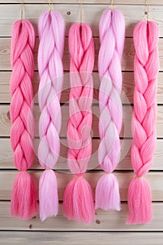 Kanekalon hangs on a wooden background of pink, fuchsia red in different shades similar