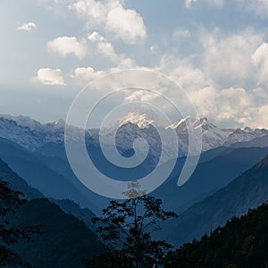 Kangchenjunga mountain with clouds above. Among green hills and trees that view in the evening in North Sikkim, India