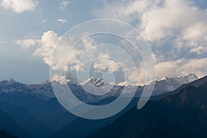 Kangchenjunga mountain with clouds above. Among green hills and trees that view in the evening in North Sikkim, India