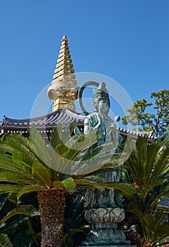 Kannon statue and the curved pagoda roof with golden sorin at Isshinji Temple. Tennoji. Osaka. Japan