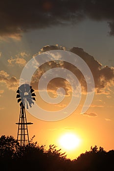 Kansas colorful orange and yellow sunset with clouds and a Windmill silhouette