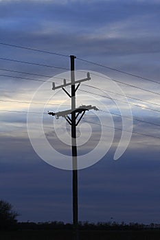 Kansas powerline silhouette at sunset with clouds west of Nickerson Kansas USA out in the country.