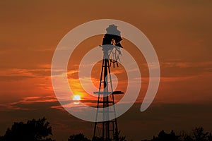 Kansas Windmill Silhouette with a Blazing orange Sunset with the Sun and Sky.