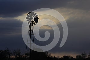 Kansas Windmill sillhouette with storm clouds out in the country.