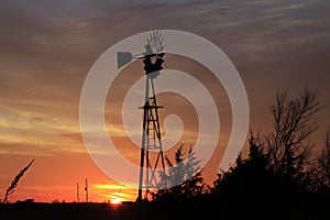 Kansas Windmill sunset with a tree silhouette with a colorful sky