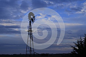 Kansas Windmill sunset with a tree silhouette with a colorful sky