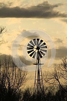 Kansas Windmill sunset with a tree silhouette with a colorful sky