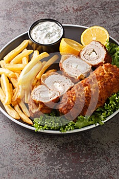 Karageorge Schnitzel Serbian Stuffed Cutlet served with french fries and tartar sauce close-up in a plate. Vertical