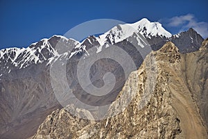 Karakoram mountain-specific landscape with yaks grazing on meadows between green mountain passes crossed by rivers and snow-capped