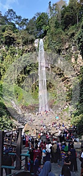 KARANG ANYAR INDONESIA, JULY 14 2019 : high waterfall and beautiful between trees. people are visiting the waterfall