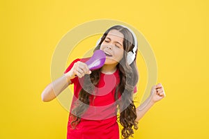 Karaoke star. Cute little girl pretending singing karaoke on yellow background. Adorable child performing karaoke song