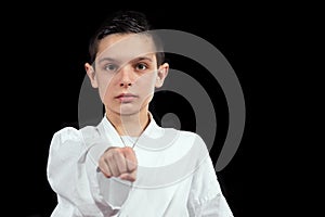 Karate boy in white kimono fighting isolated on black background