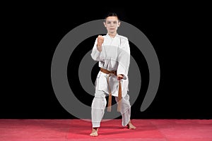 Karate boy in white kimono fighting isolated on black background