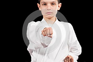 Karate boy in white kimono fighting isolated on black background