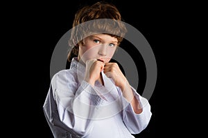 Karate boy in white kimono isolated on black