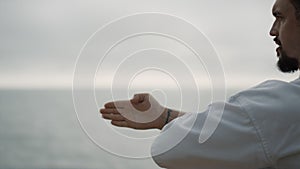 Karate fighter training martial arts techniques on beach. Man practice punches.