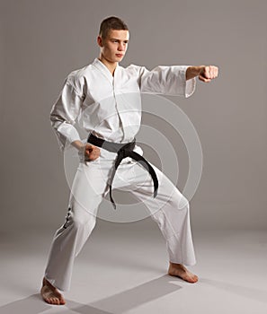 Karate in a fighting pose on the grey backgroun.