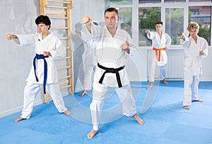 Karate instructor demonstrating kata sequence of movements to group of teenagers