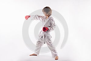 Karate kid wearing kimono and red boxing gloves doing exercises