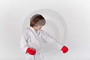 Karate kid wearing kimono and red boxing gloves and exercising
