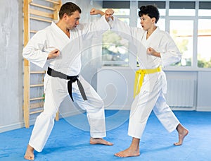 Karate lesson for teenager - guy and trainer are sparring in gym