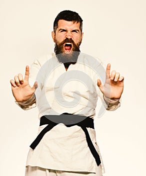 Karate man with angry face in uniform. Oriental sports concept. Jiu Jitsu master with black belt