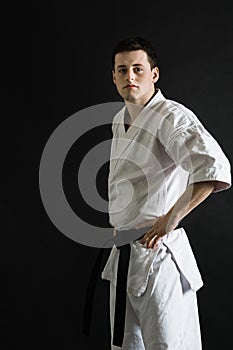 A karateka strikes or stands in a stance. Martial arts. Shidokan karate. Fighter in the studio. Kimono guy on a black background.