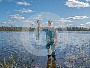 Man with catched fish in a lake. Ecotourism, visiting fragile, undisturbed natural areas. Active photo