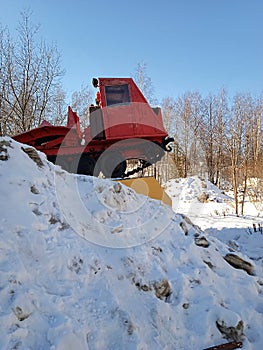 Karelian red tractor is behind a snowy mountain