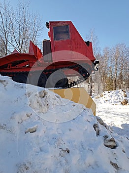 Karelian red tractor is behind a snowy mountain