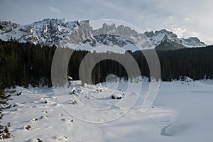 Karersee, Lago di Carezza in Winter with Latemar covered in Snow in the Background. Latemar Mountain range in the Dolomites in Sou