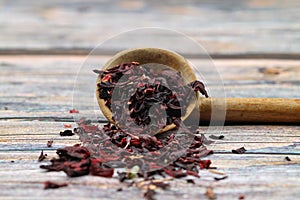 Karkade tea. Hibiscus tea leaves in wooden spoon isolated on wooden background. File contains clipping path. Top view. Selective